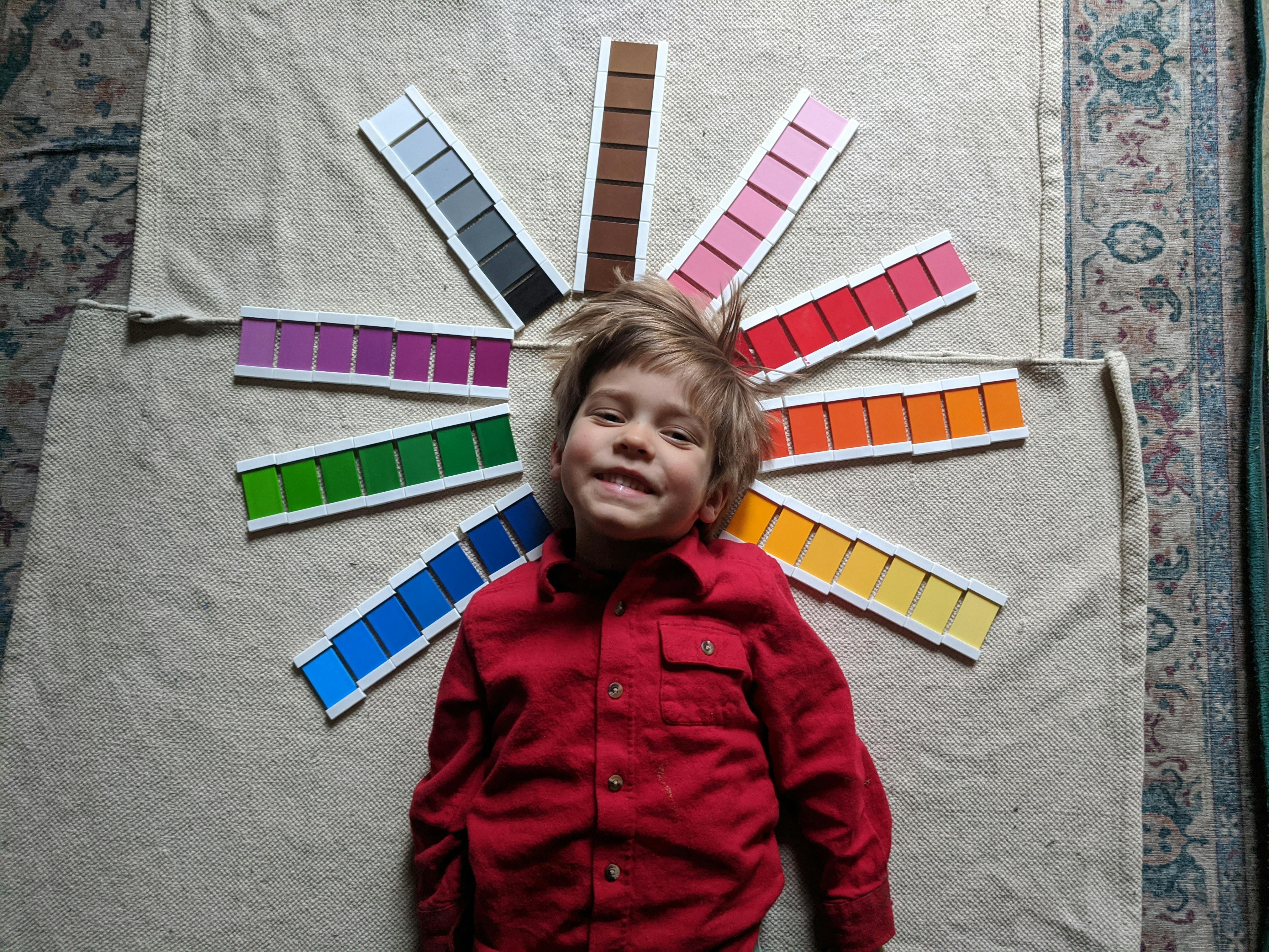 Child lying on a mat with color swatches fanned out around their head