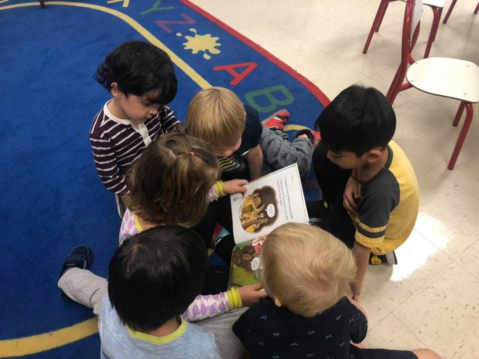 Group of children looking at a book on a rug