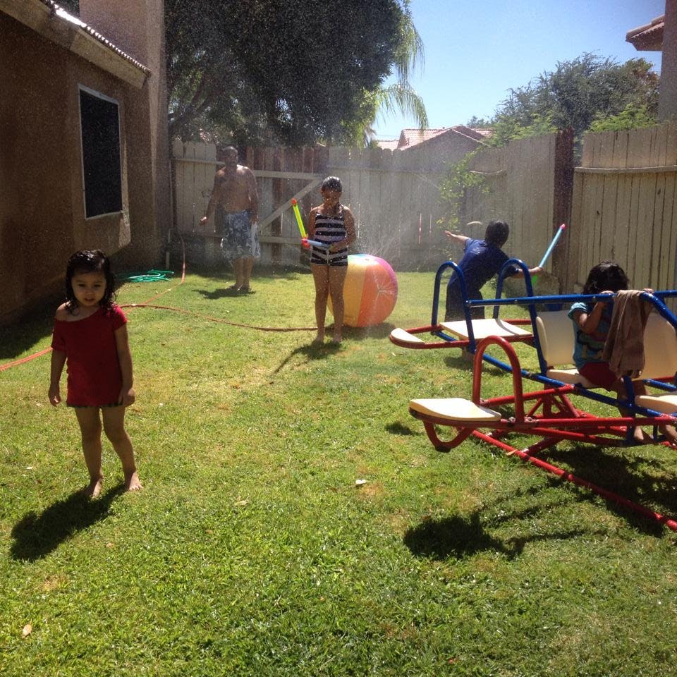 People playing with water in a grassy backyard