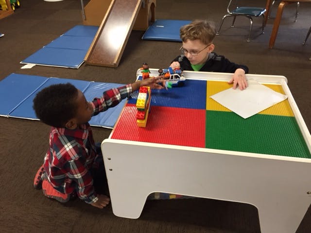 Two children playing with toys at a table