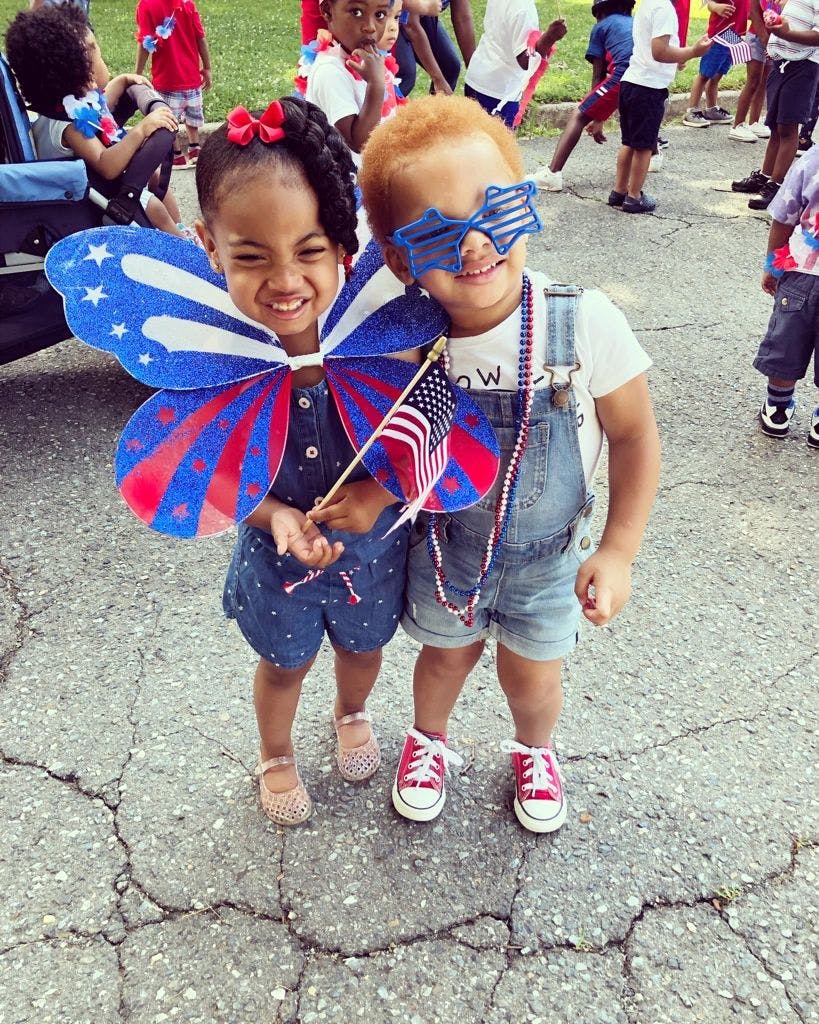 Two children in patriotic attire holding American flags