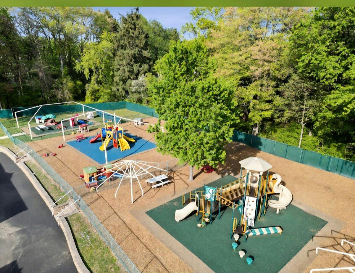Aerial view of a fenced playground with multiple climbing structures and slides