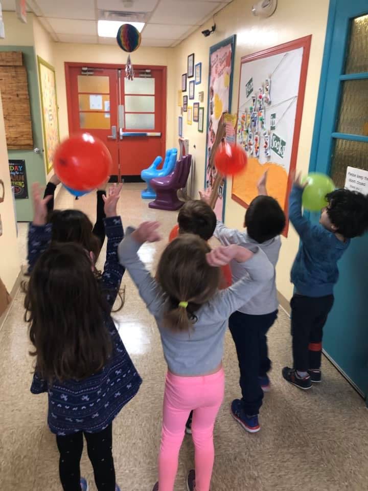 Children playing with balloons in a hallway