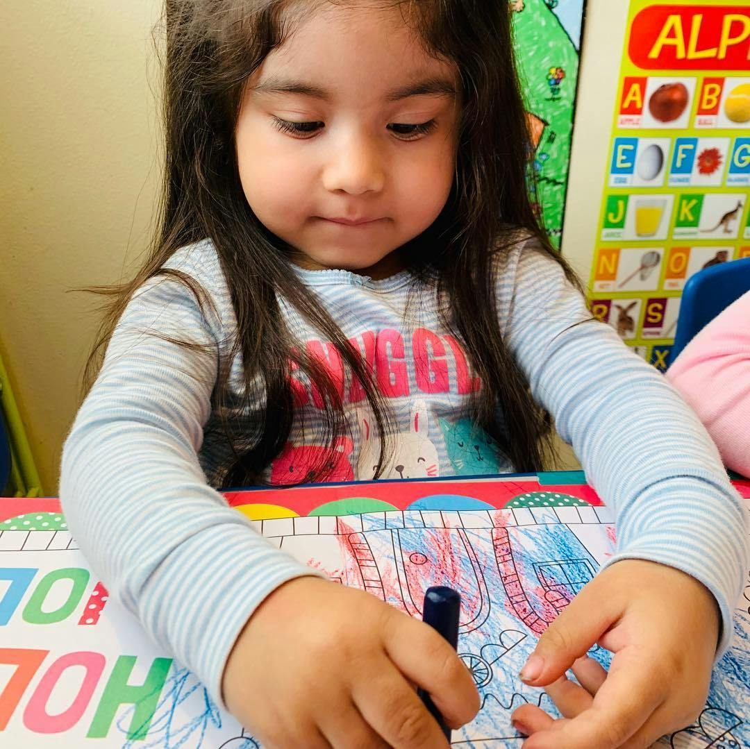 Child coloring on paper with a crayon