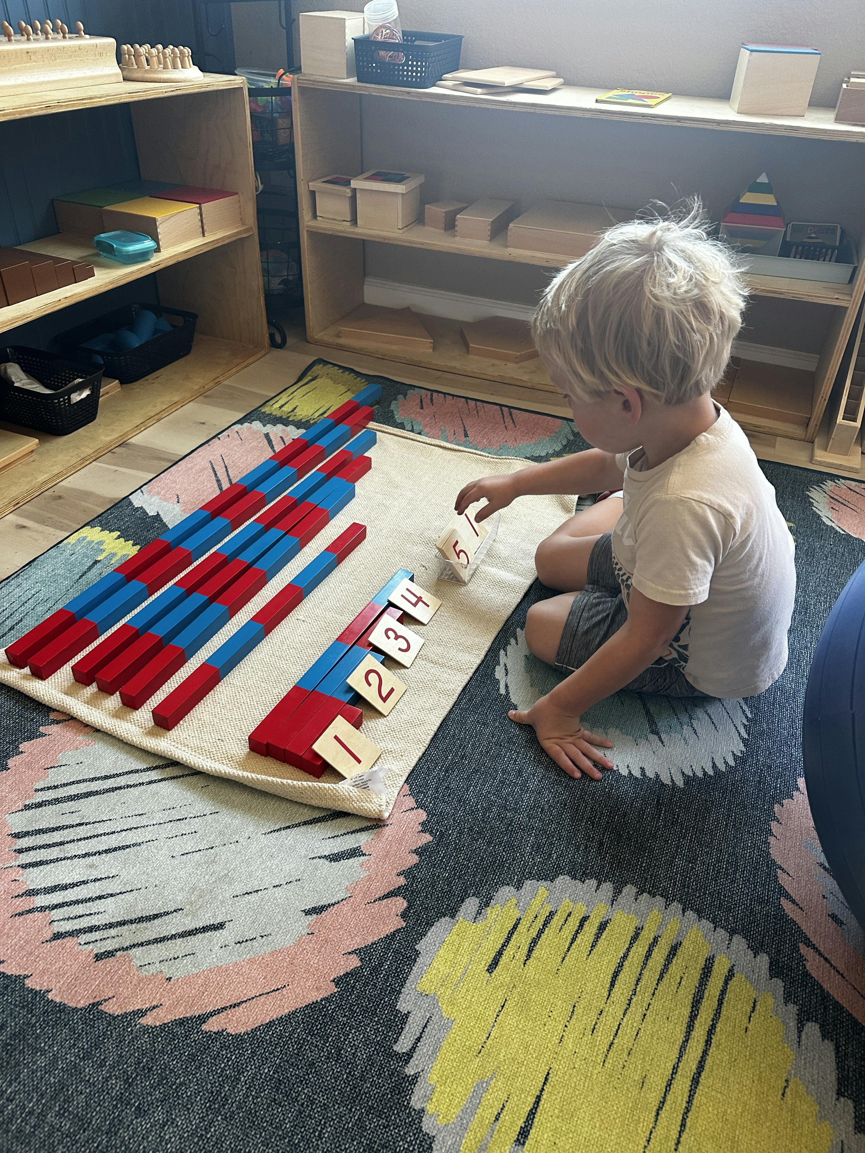 Child playing with red and blue math rods and number cards on a rug