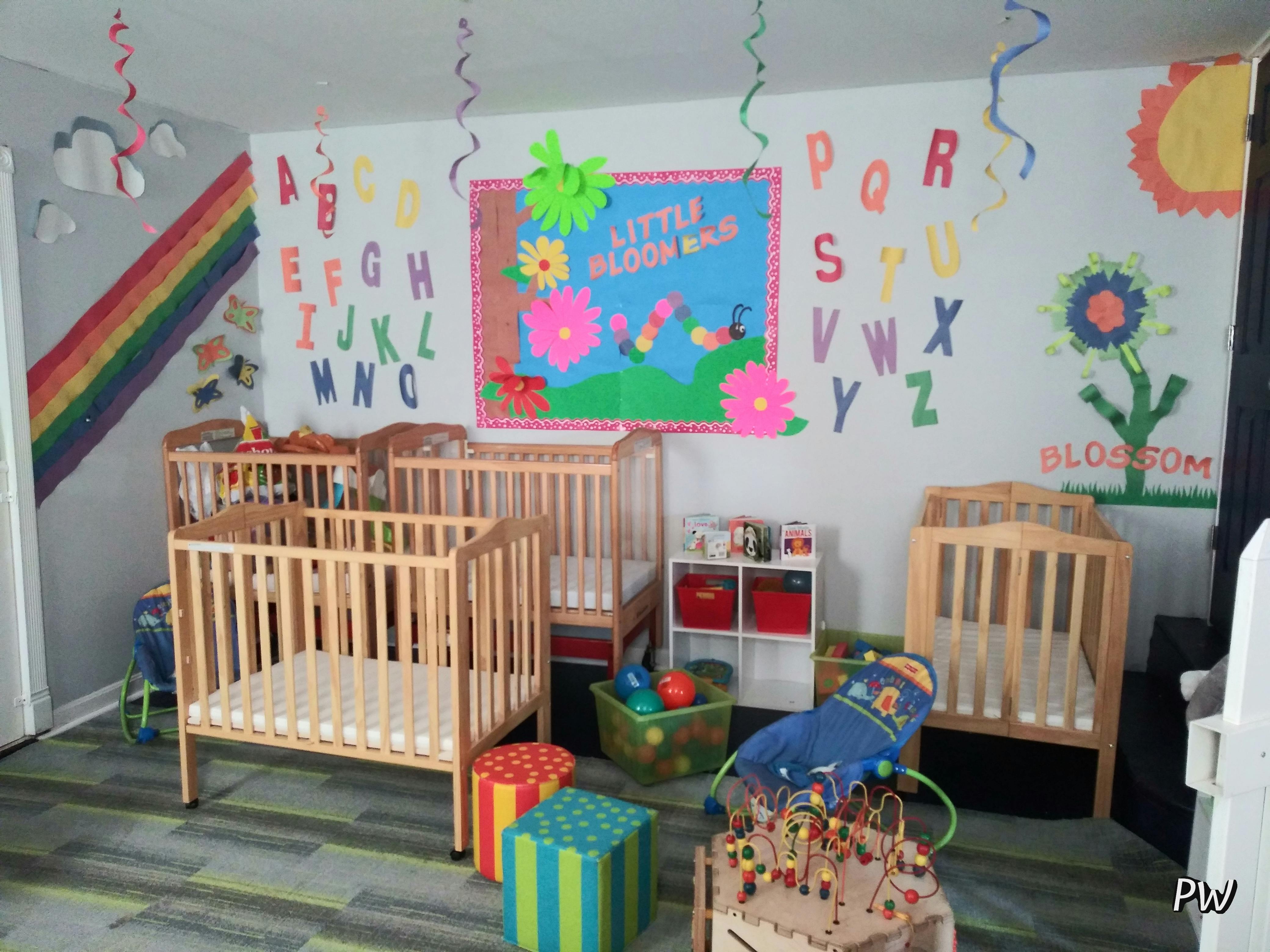 Multiple cribs in a brightly decorated room with alphabet letters on the wall