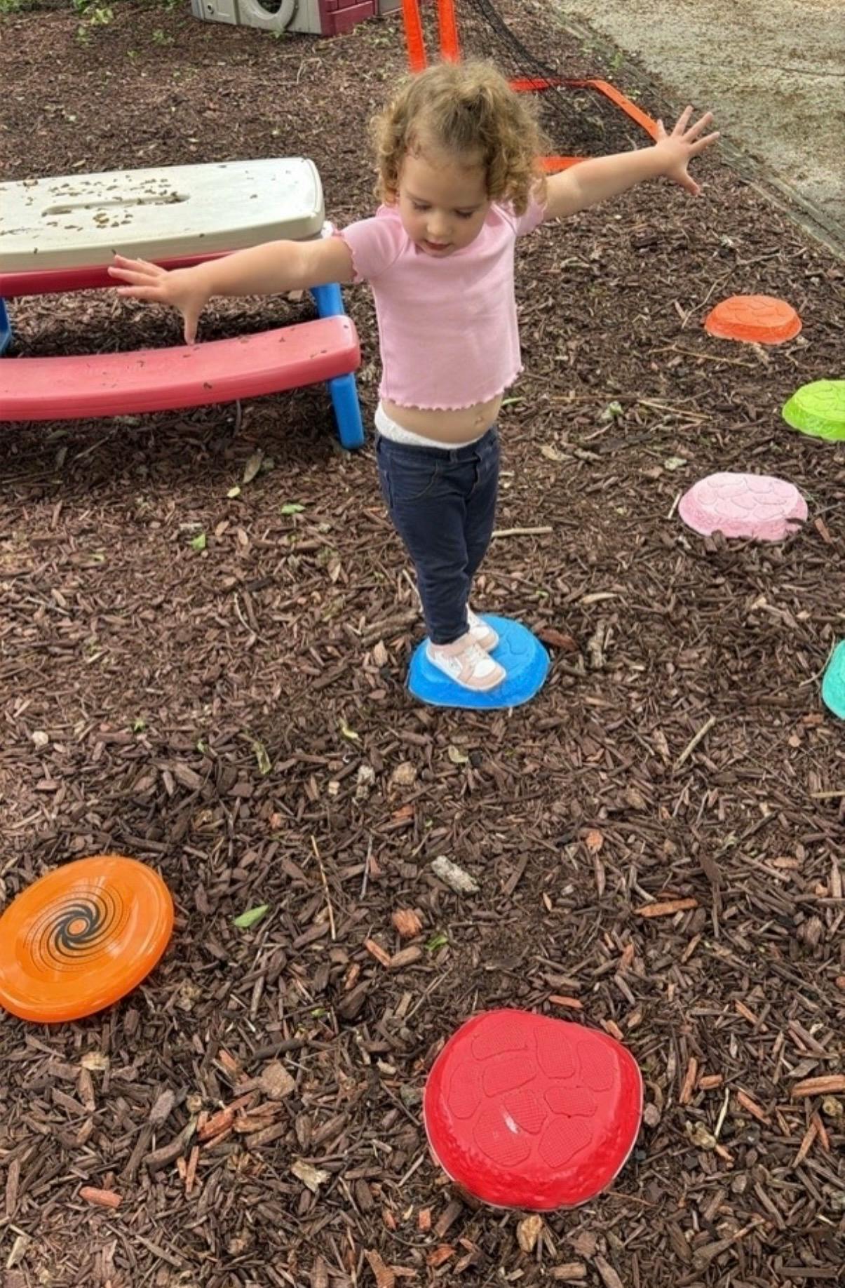Child balancing on a stepping stone in a playground