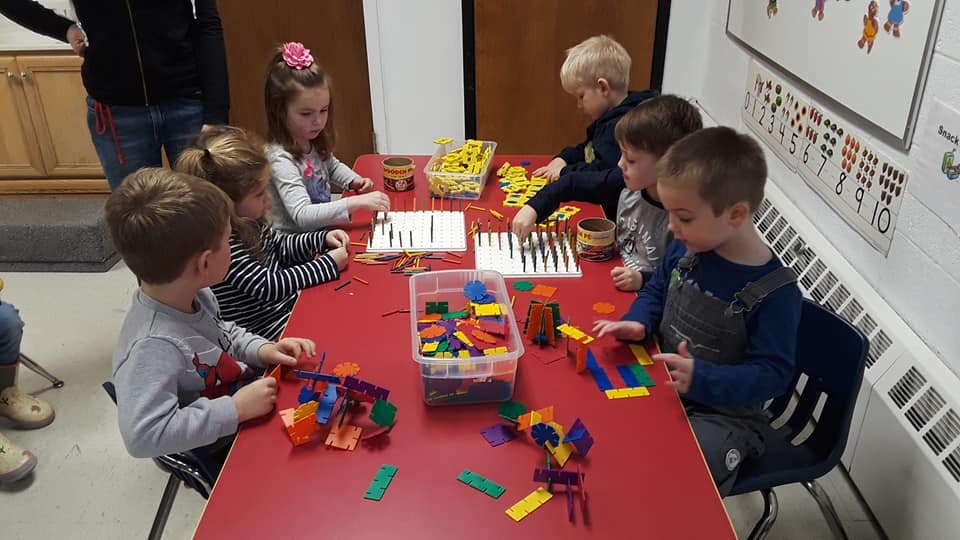 Children playing with building blocks at a red table