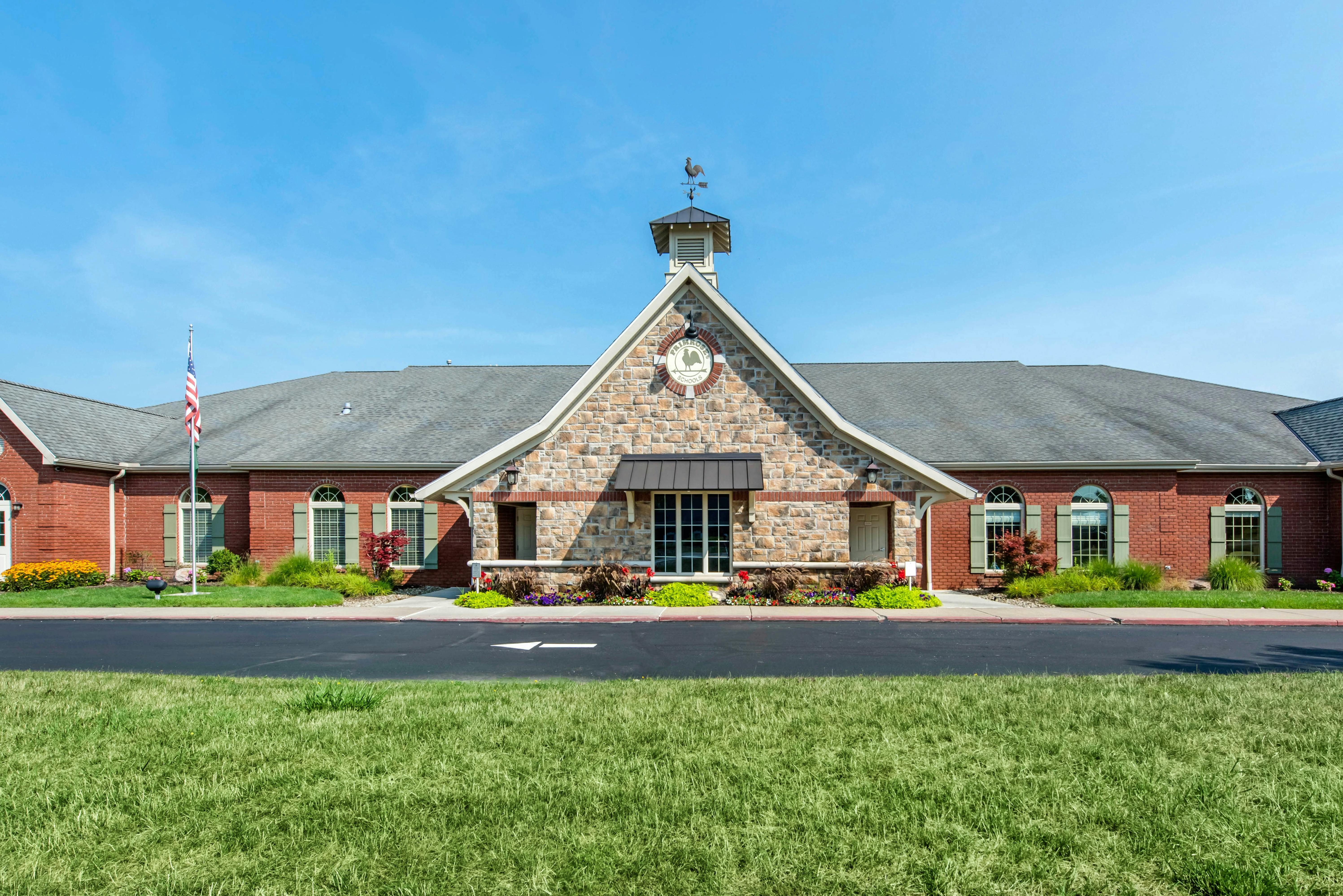 Brick building with a stone-faced gabled entrance and a weather vane on the roof
