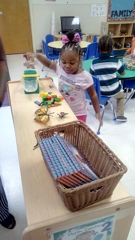 Child playing with blocks and toys on a table in a classroom