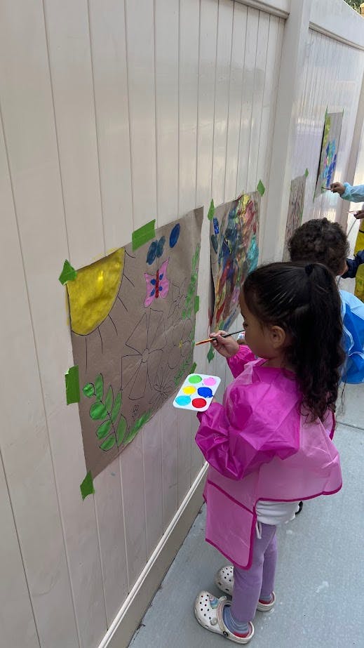 Child painting on paper taped to a wall