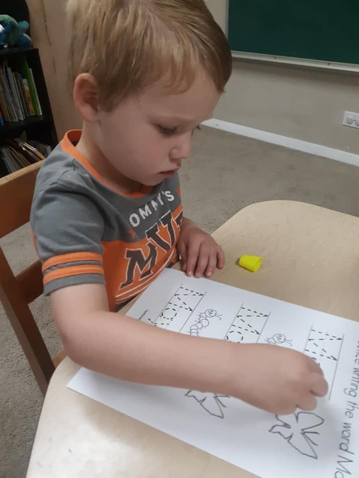 Child tracing letters on a worksheet at a table