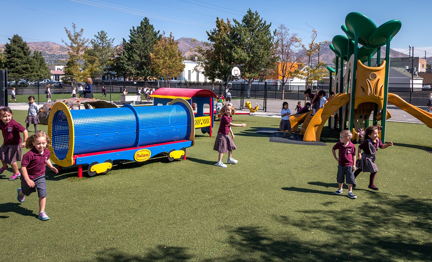 Children playing on a playground with a train structure and slides