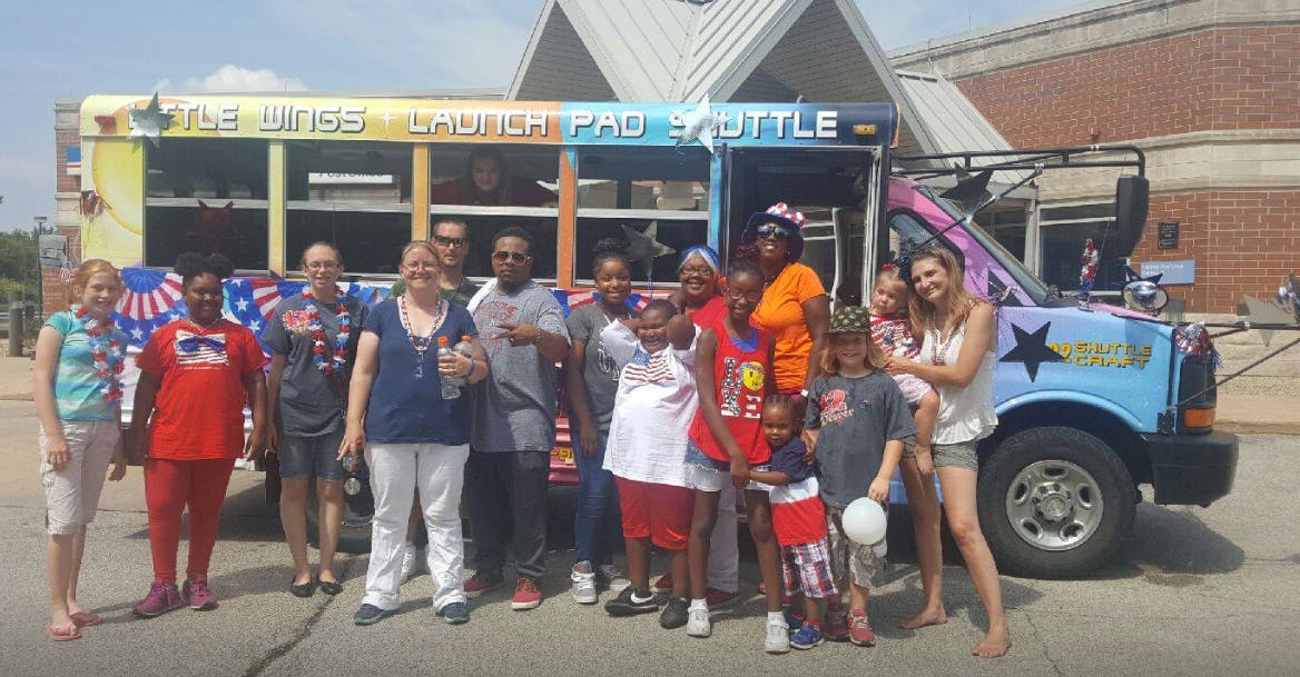 Group of people and children standing in front of a colorful bus