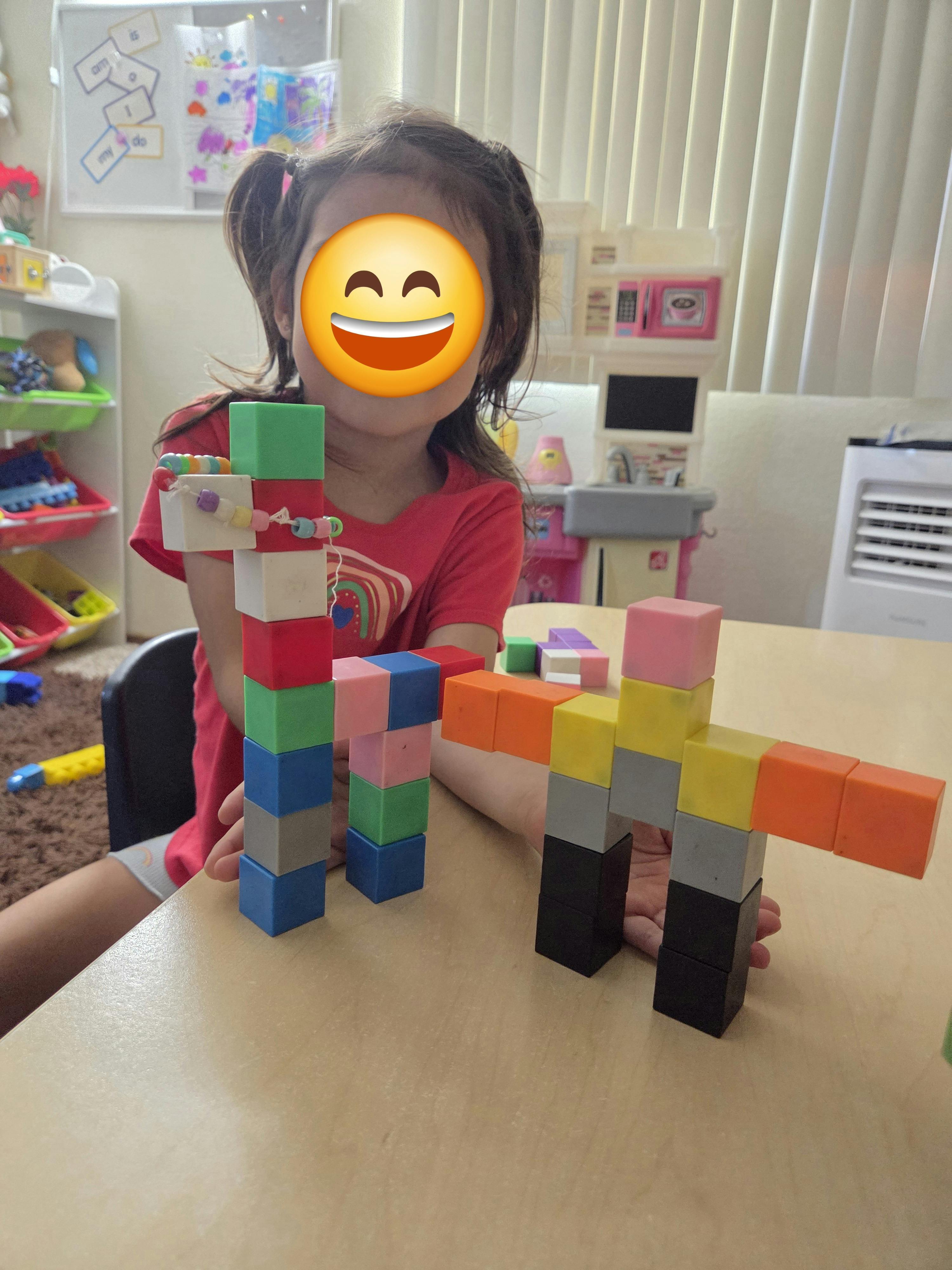Child building figures with colorful plastic cubes on a table