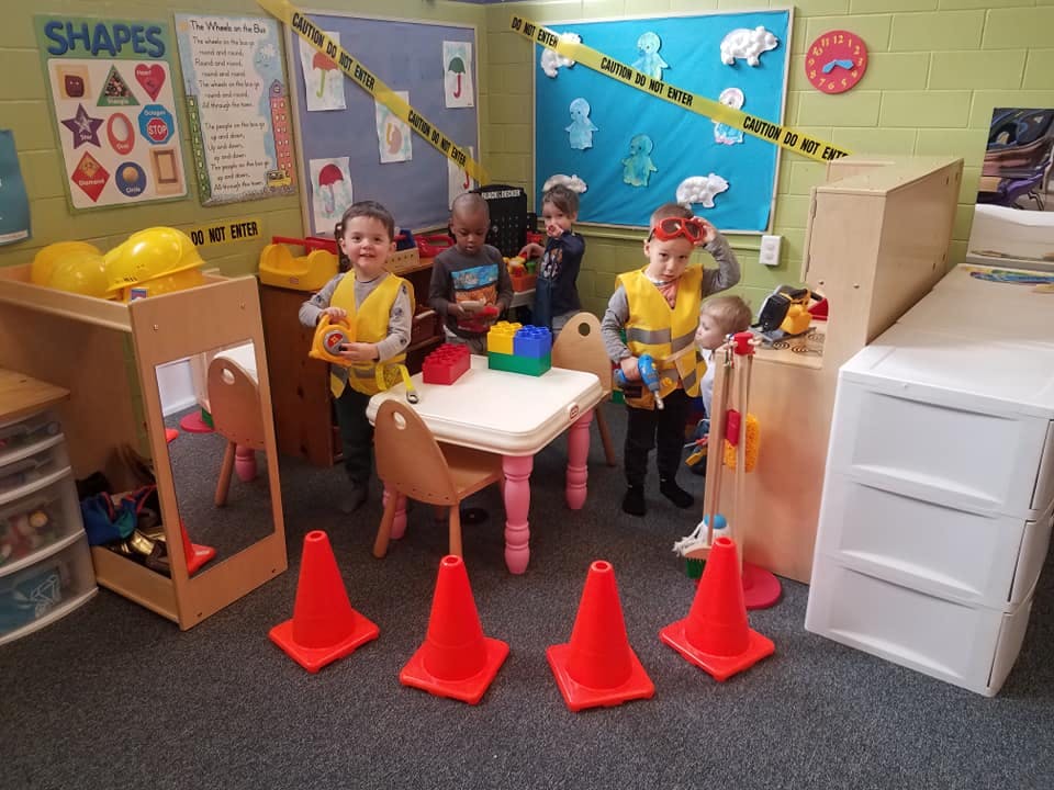 Children playing in a classroom with construction-themed toys