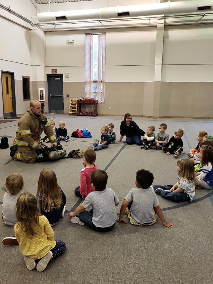 Firefighter kneeling with children sitting in a circle