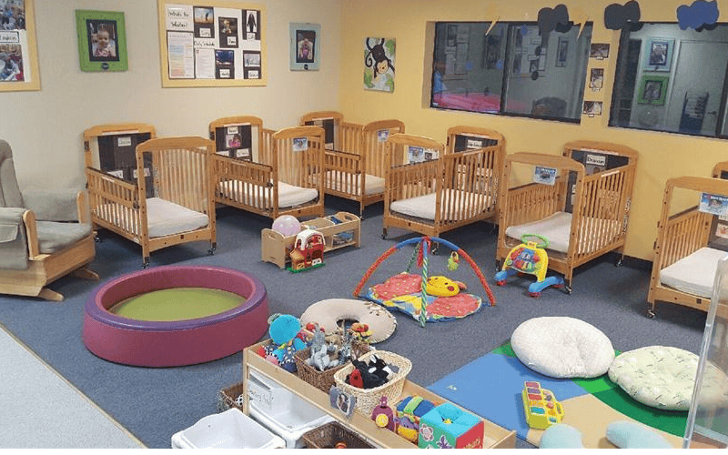 Cribs and baby play items in a brightly lit room