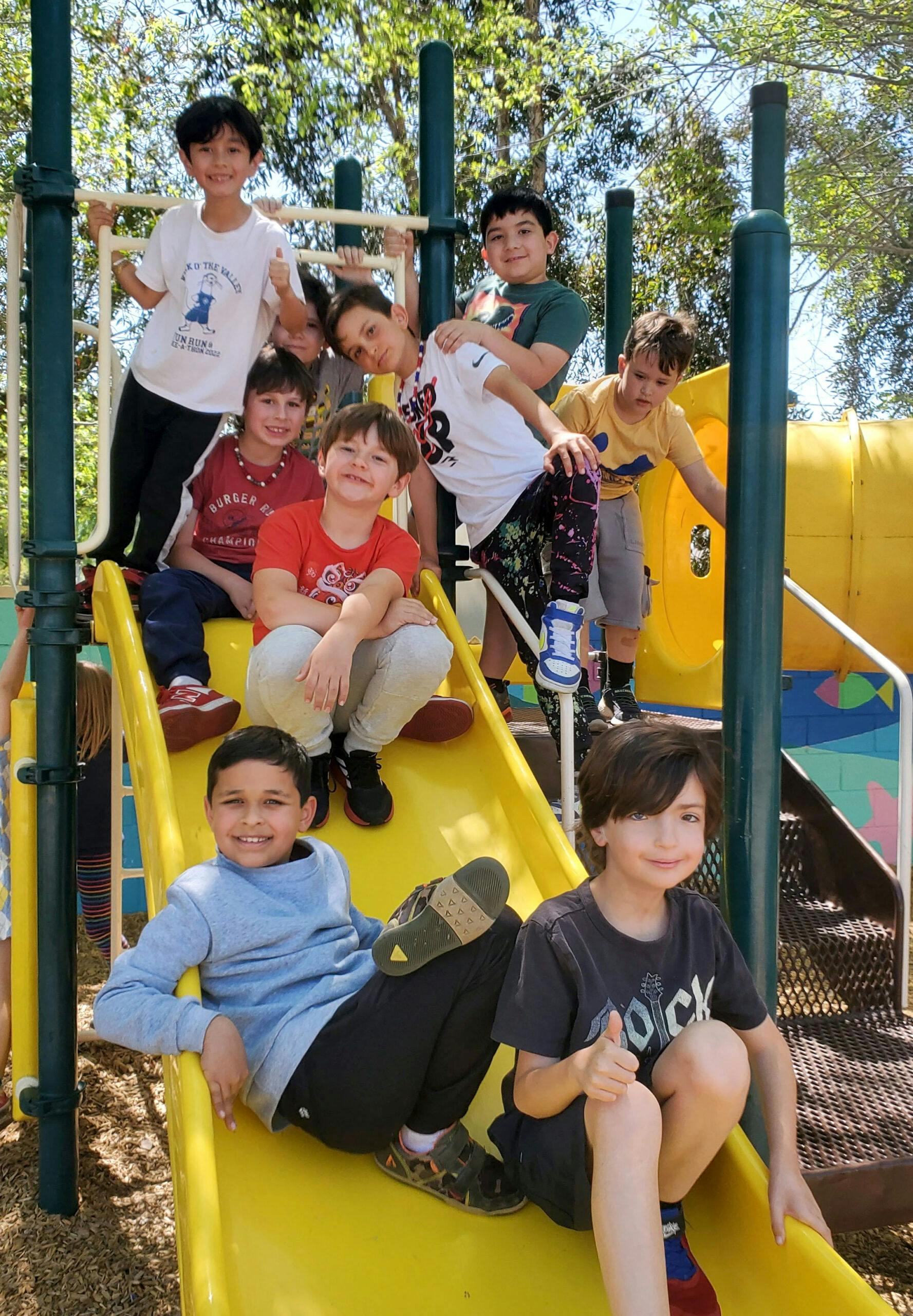 Children on a yellow playground slide and climbing structure