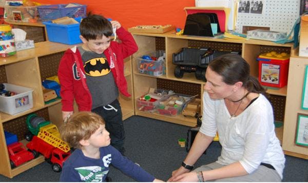 Adult and two children interacting in a classroom