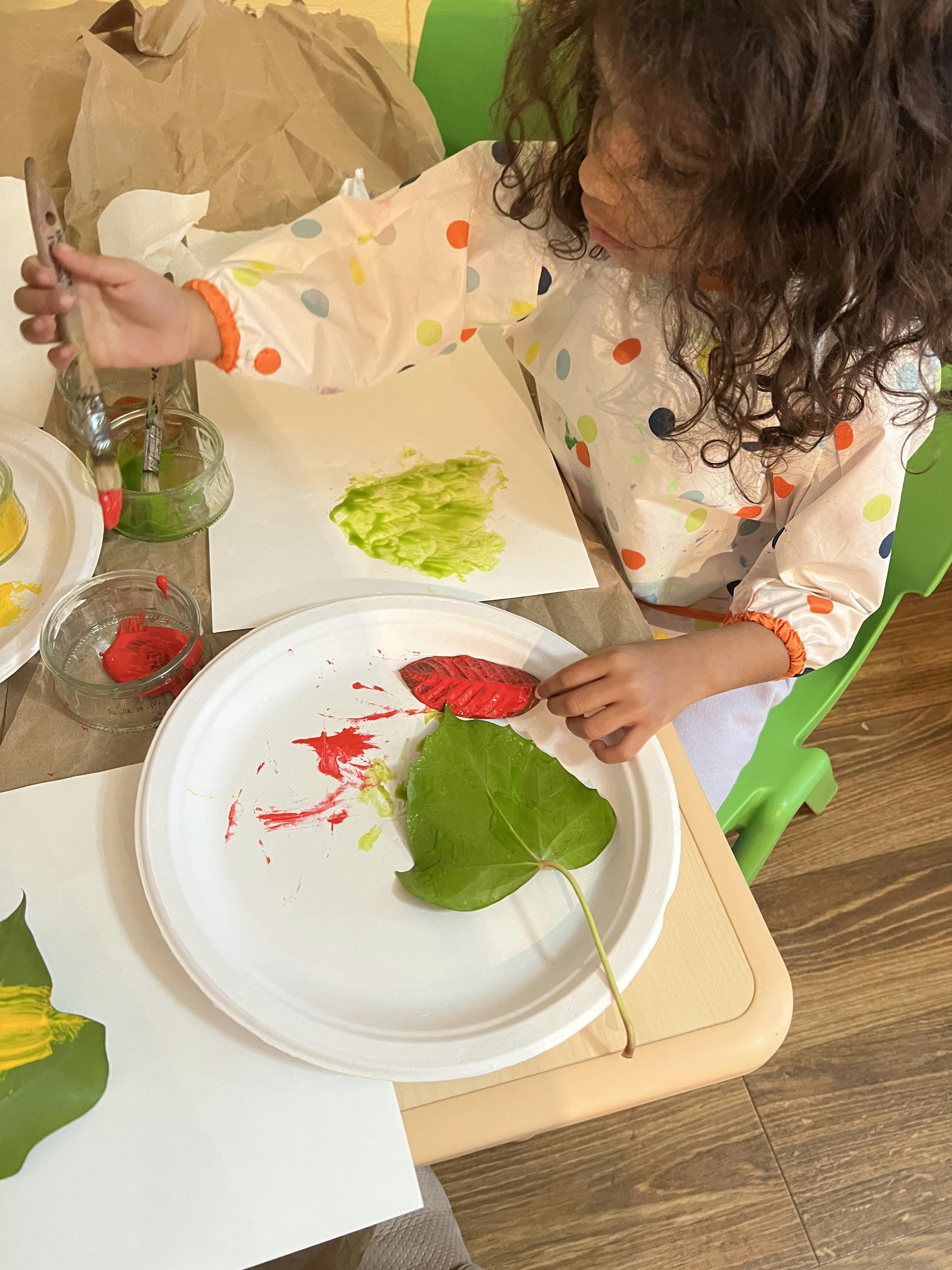 Child painting a leaf red