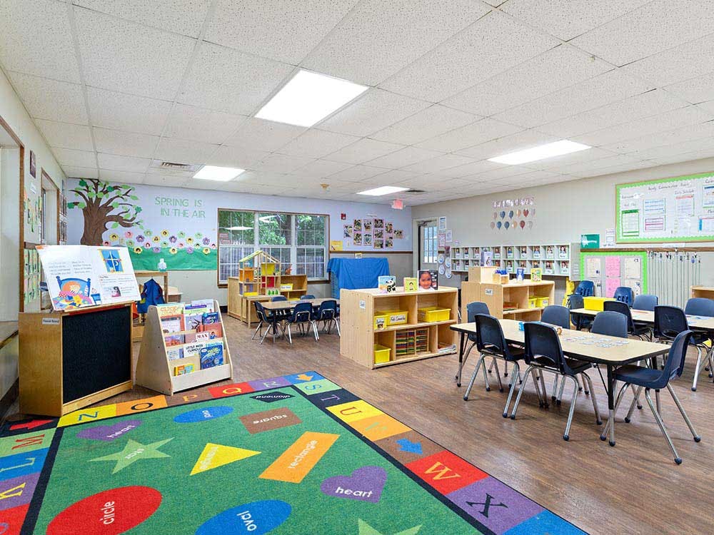 Colorful rug in an empty classroom with small tables and chairs