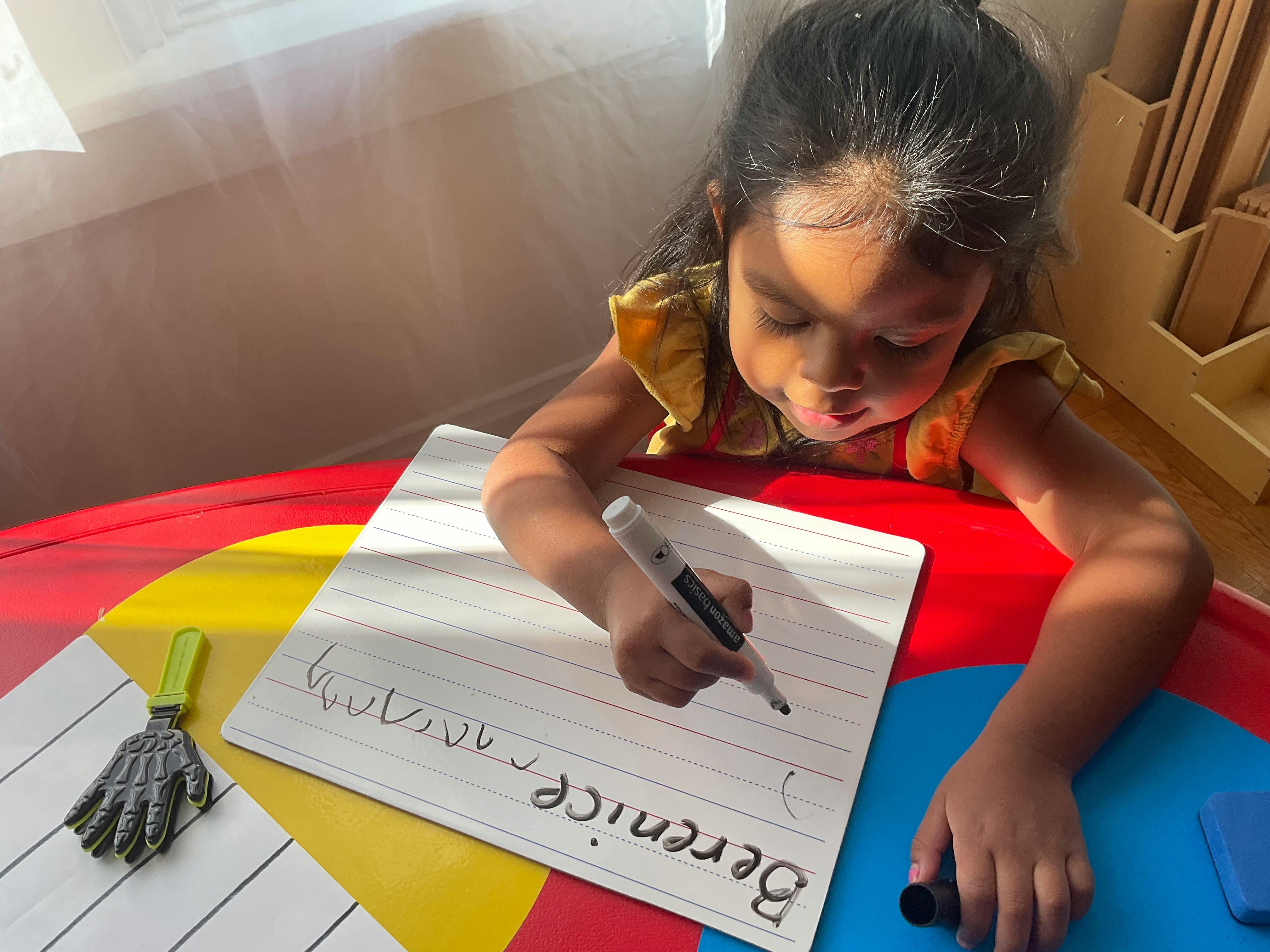 Child writing on a whiteboard with a marker