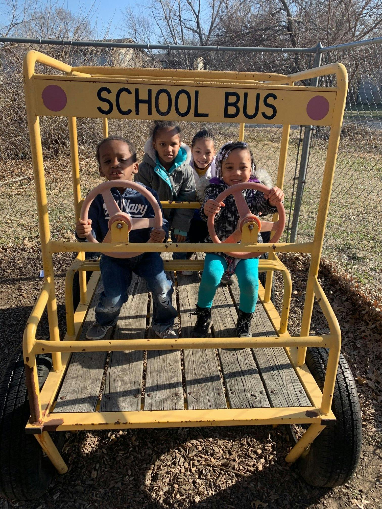 Four children playing in a yellow school bus structure