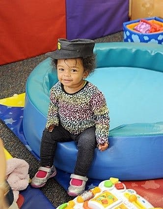 Child wearing a hat sitting on the edge of a blue inflatable pool