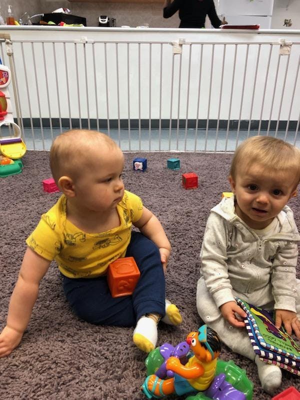 Two children sitting on a carpeted floor with toys