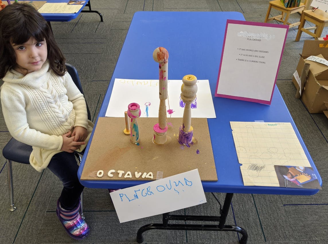 Child sitting next to a table with a craft project