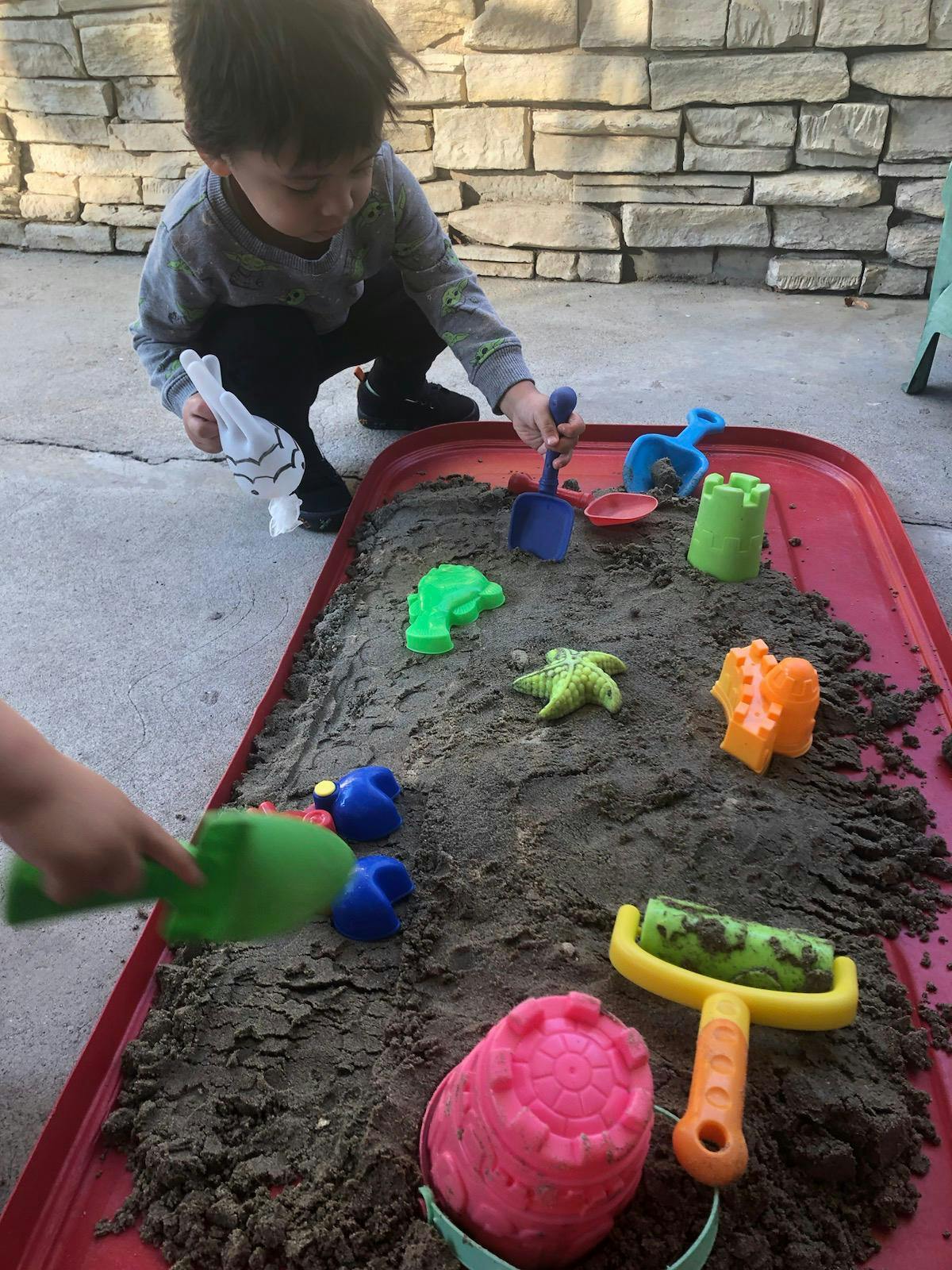 Child playing in a sandbox with sand toys