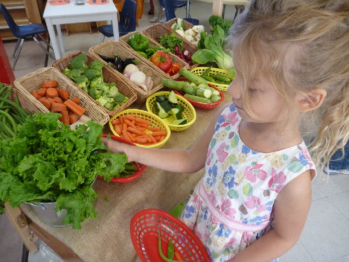 Child reaching for vegetables on a table