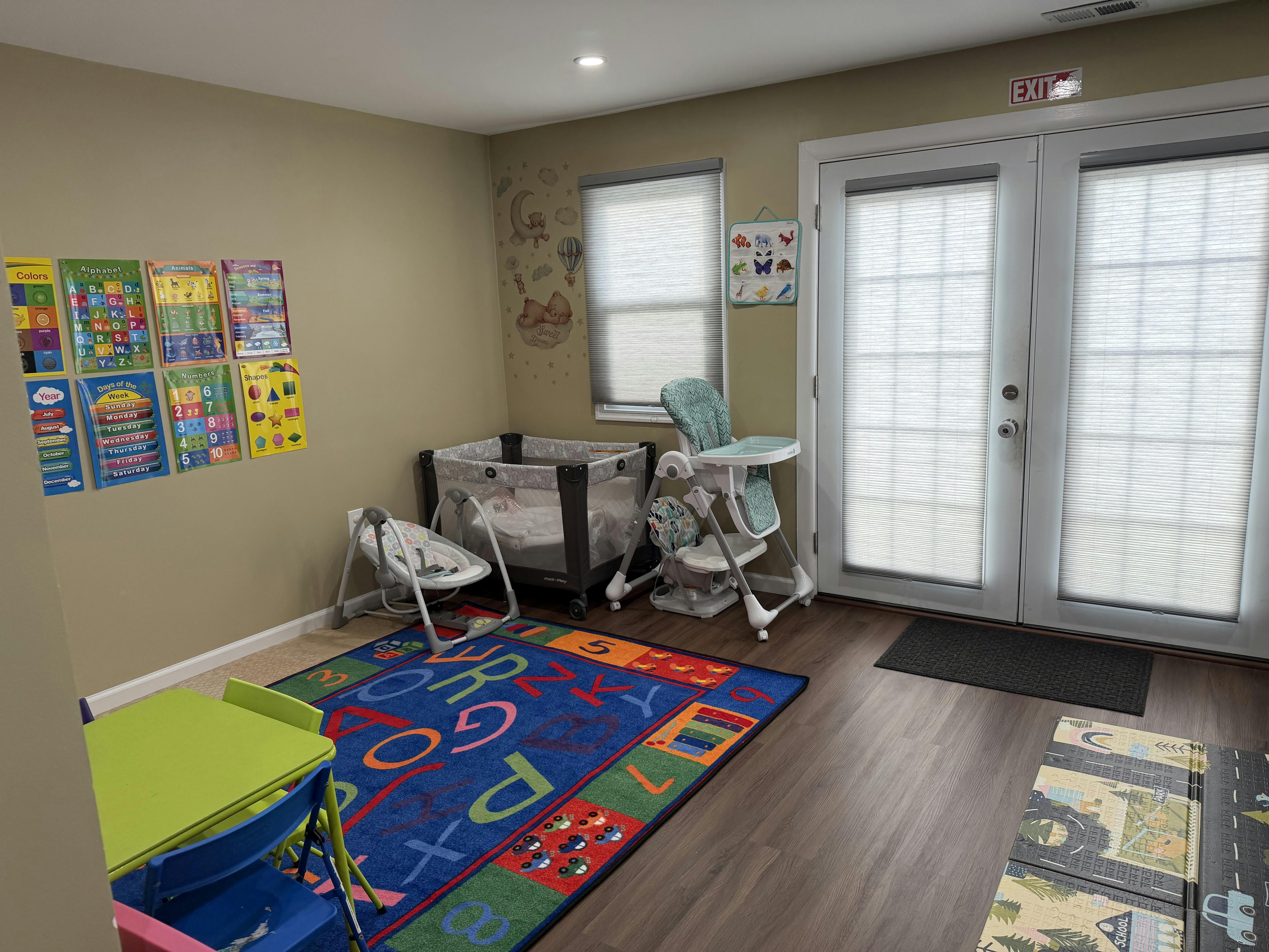 Child's play area with a colorful rug, crib, and high chair