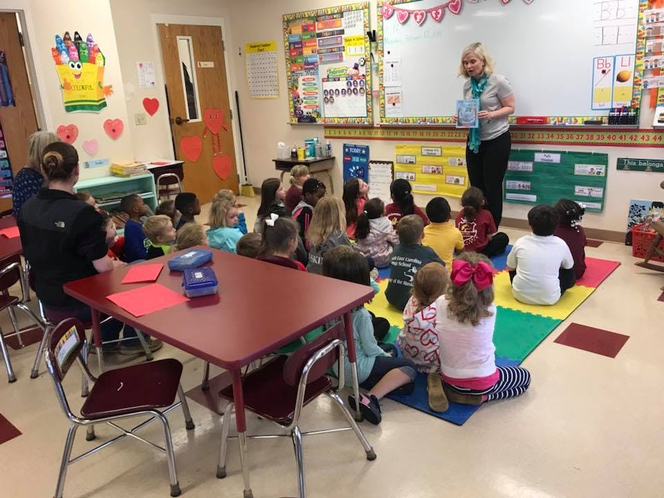 Adult reading to children seated on a mat in a classroom