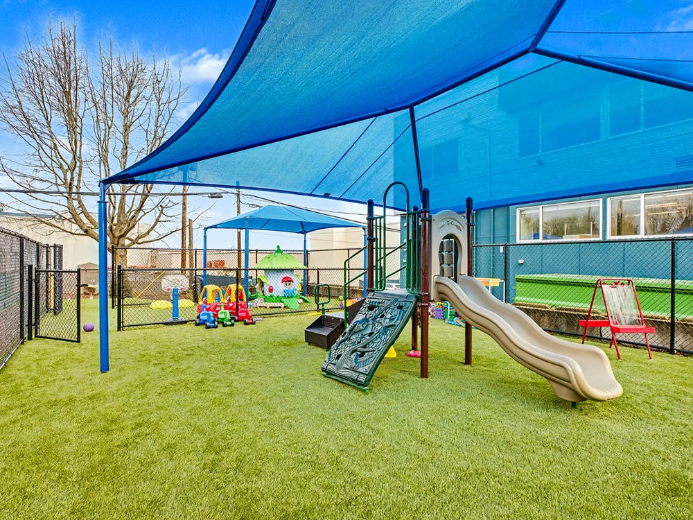 Outdoor playground with artificial turf and blue shade canopies