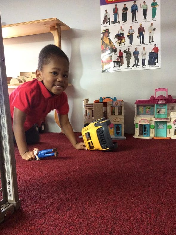 Child on hands and knees on a red carpet with toys