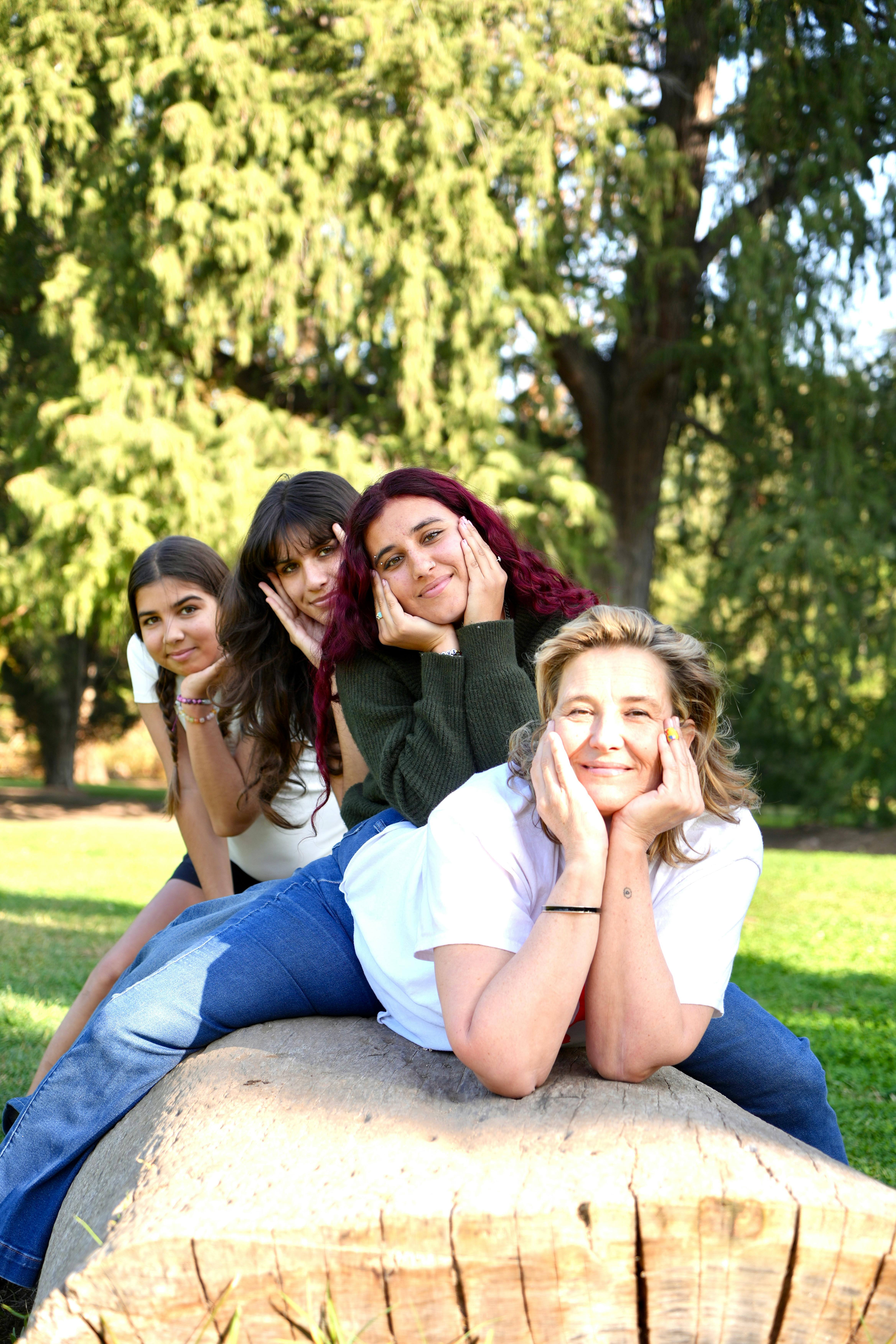 Four people posing together outdoors, resting chins on hands