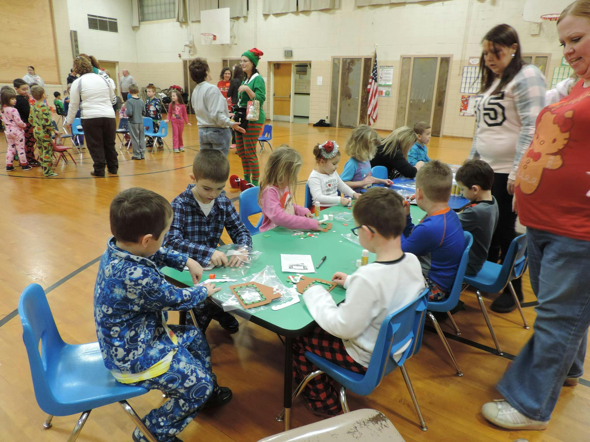 Children and adults in a large room, children seated at tables