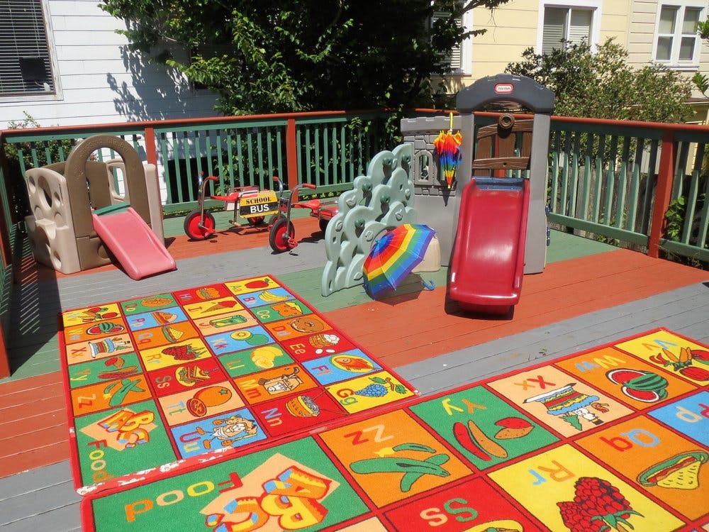 Outdoor play area with slides, play structures, and alphabet rugs