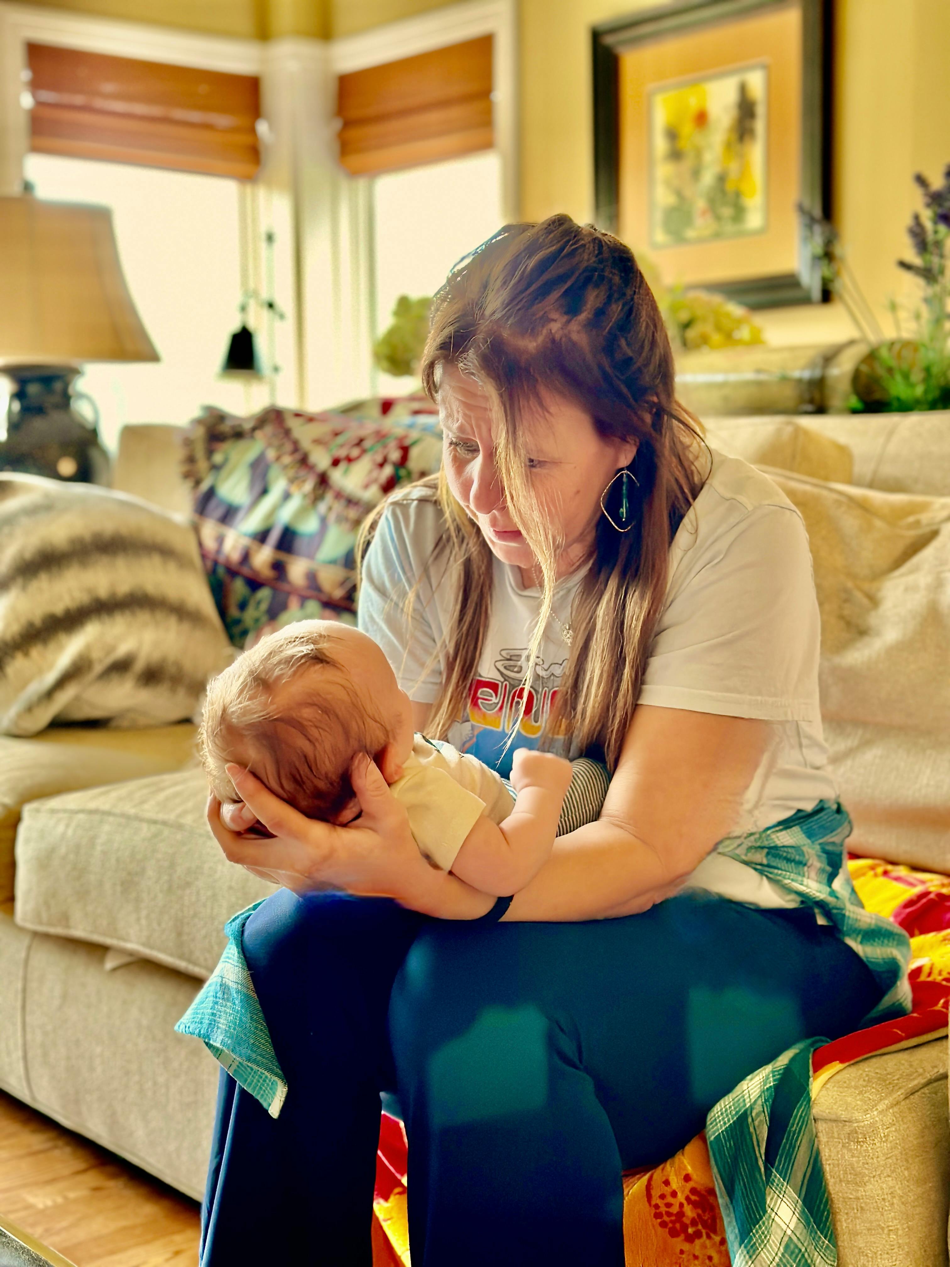 Person holding a baby while sitting on a couch