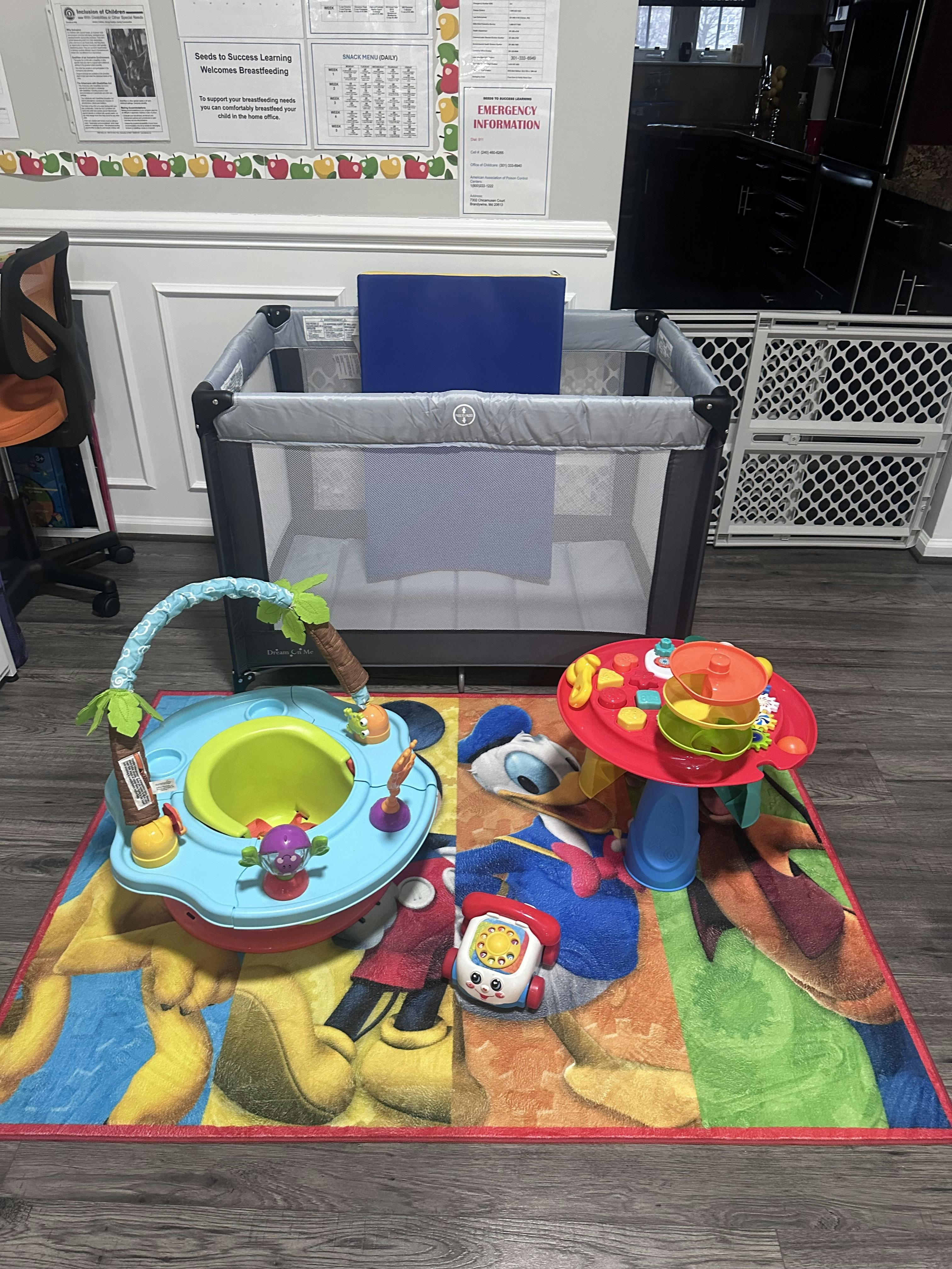 Child's playard, baby activity seat, and toy table on a colorful rug