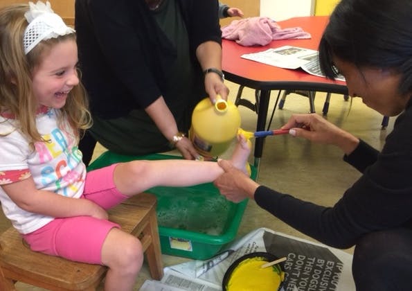 Child getting foot washed by two people