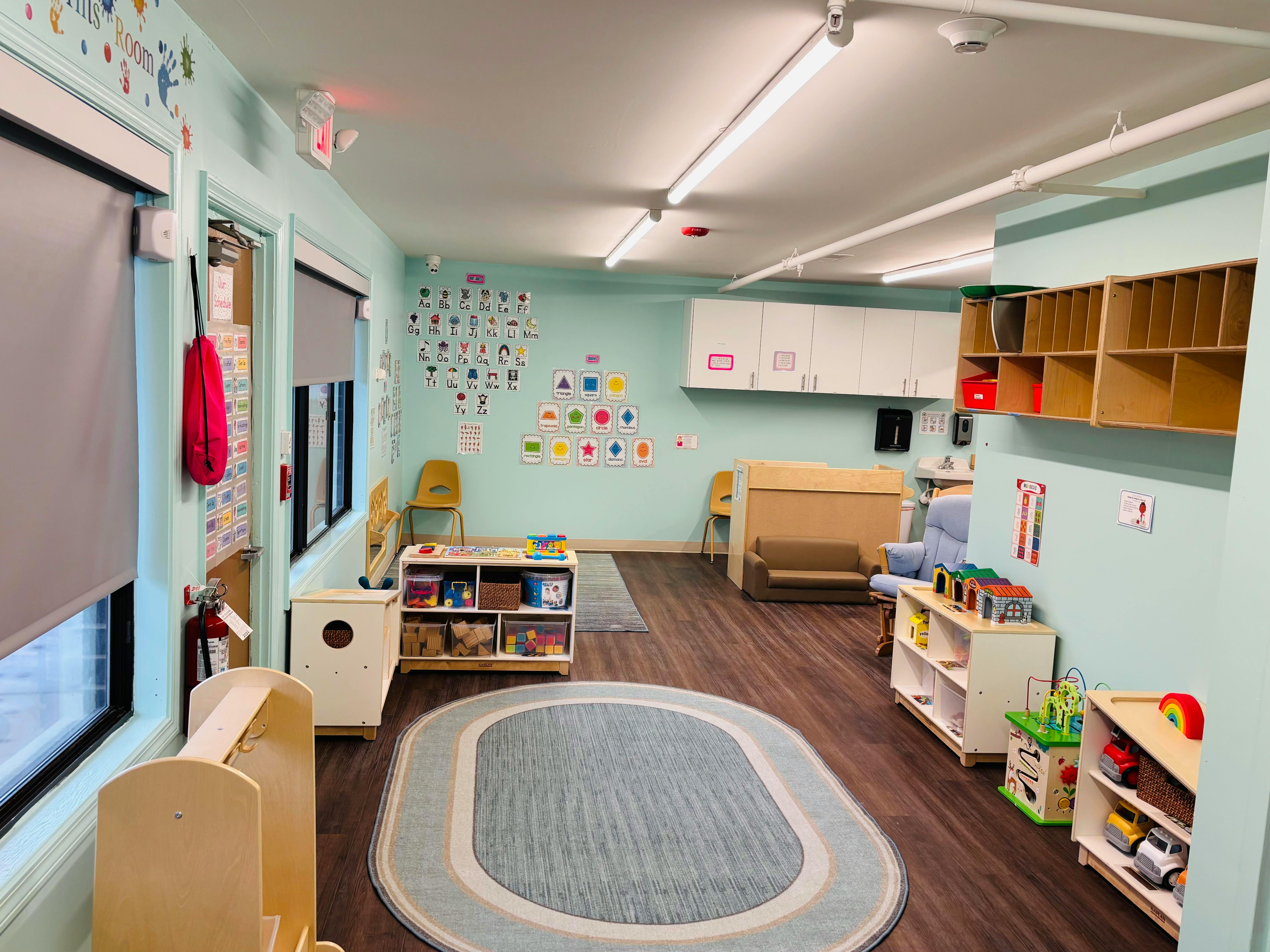 Empty classroom with light blue walls, wooden floors, and various shelves and furniture