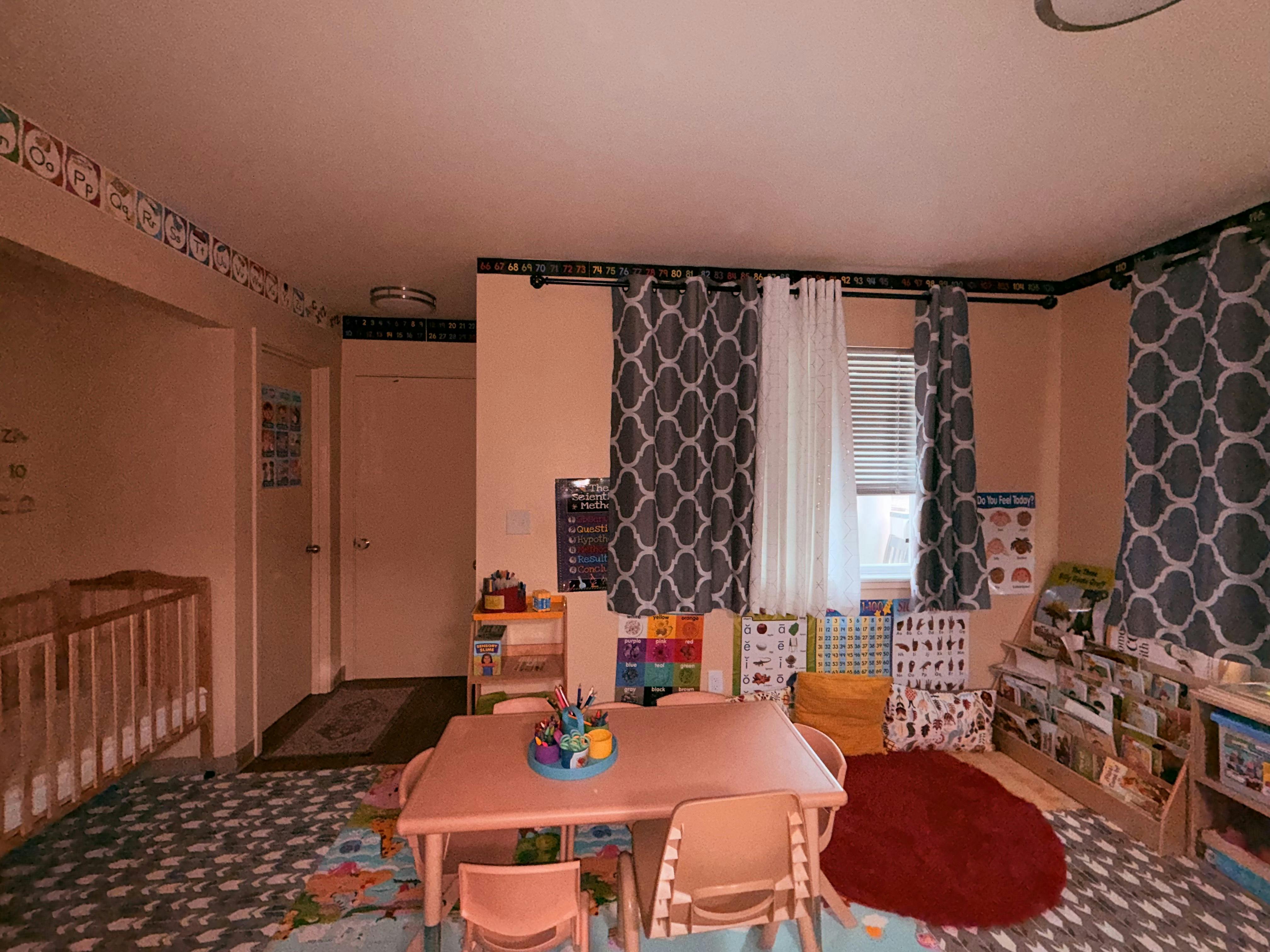 Playroom with small table and chairs, crib, and window with curtains