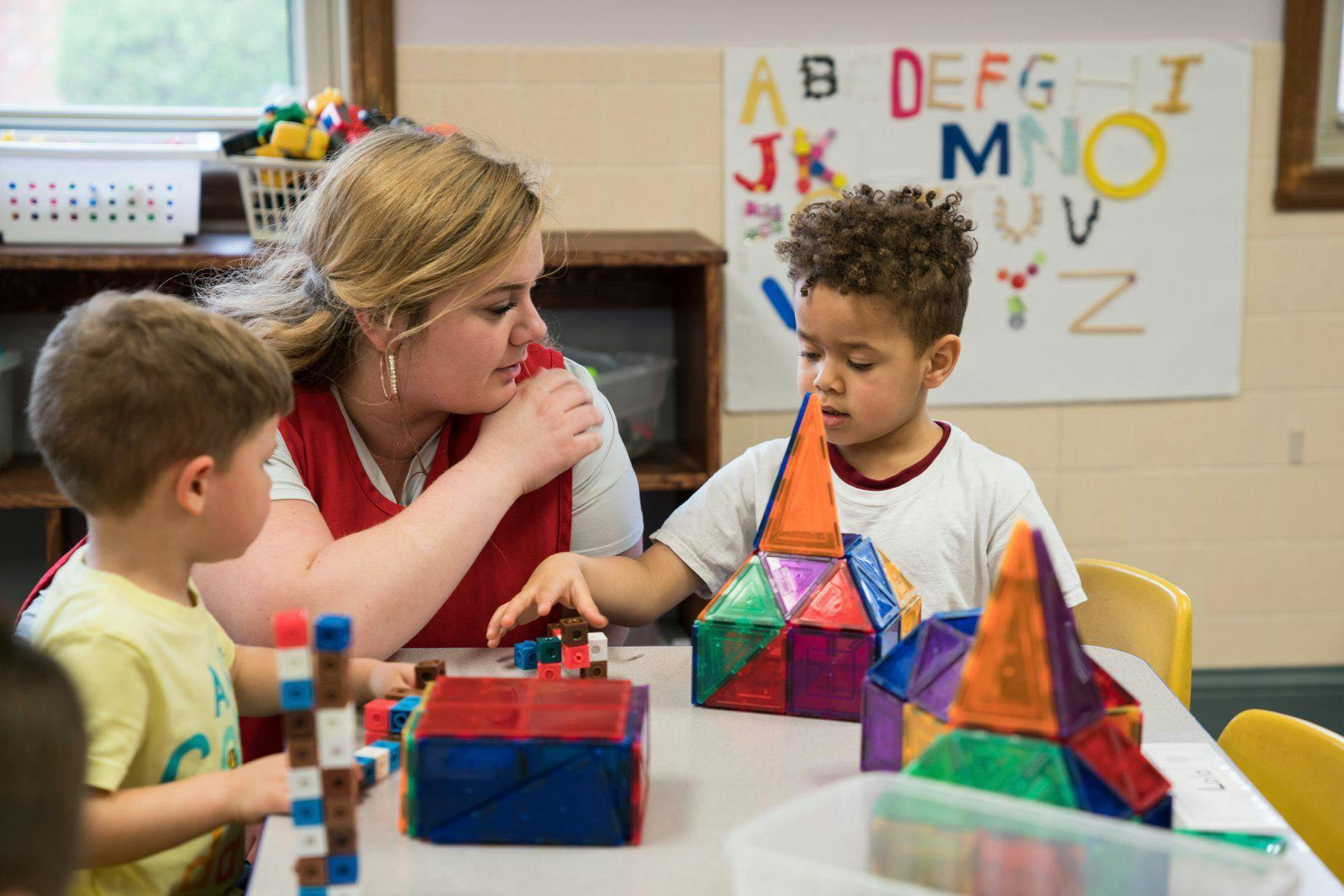 Adult and two children playing with building blocks at a table