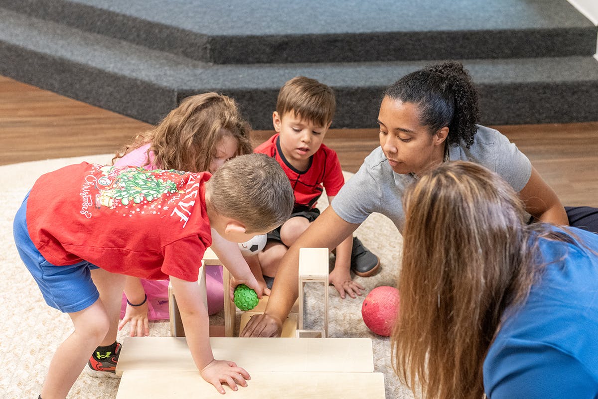 Adults and children playing with blocks and balls on the floor