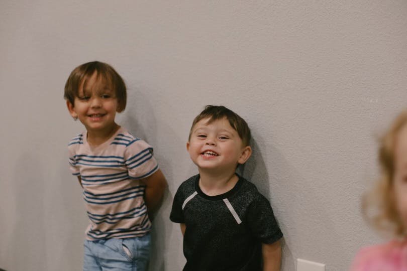 Two children standing against a wall