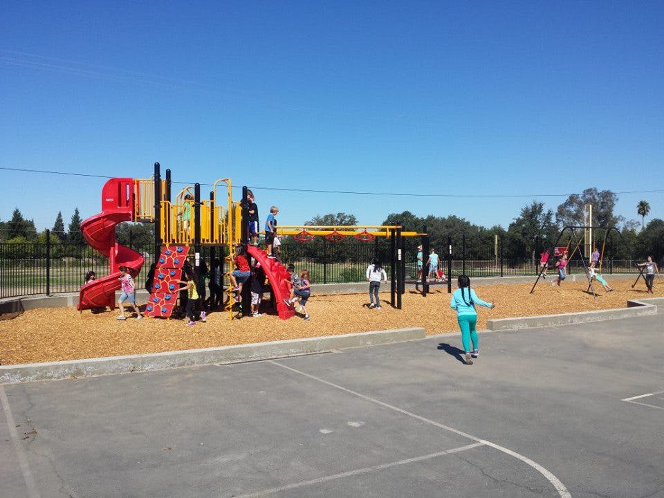 Children playing on a playground with slides and climbing structures
