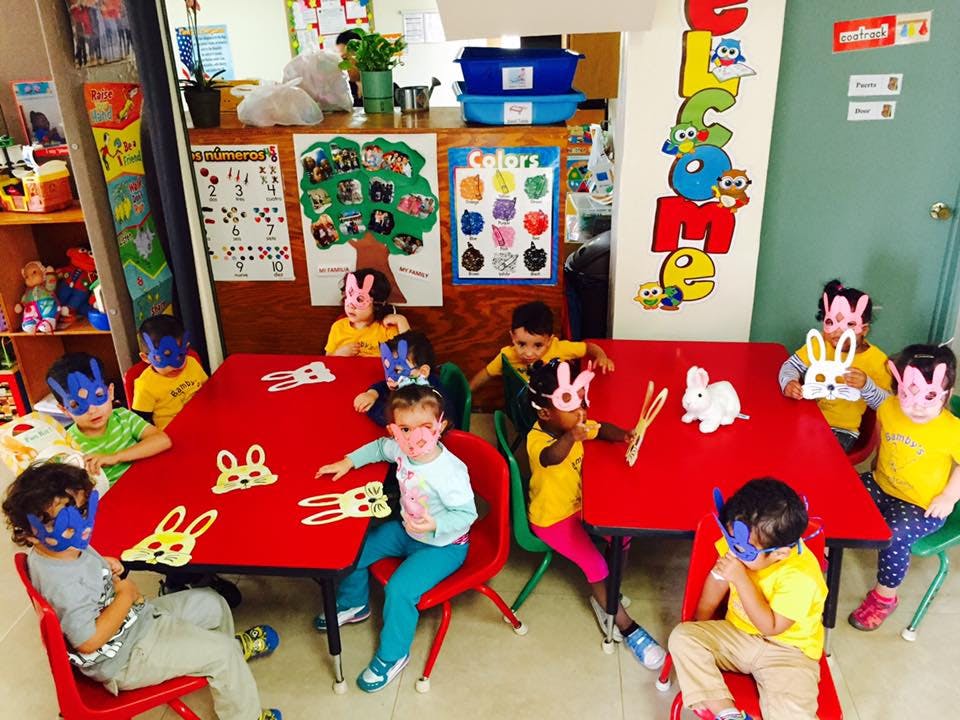 Children wearing bunny masks sitting at a red table with bunny cutouts